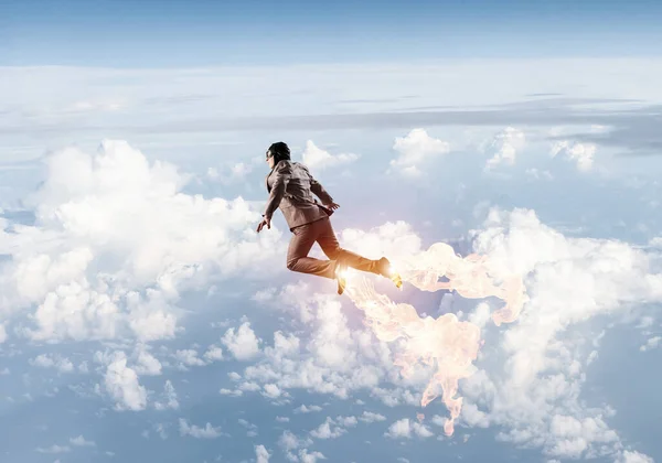 Takım elbiseli ve havacı şapkalı bir iş adamı gökyüzünde uçuyor. — Stok fotoğraf