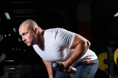 Spor salonunda dambıllarla çarpışan erkek vücut geliştirici.