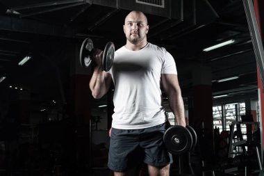 Spor salonunda dambıllarla çarpışan erkek vücut geliştirici.