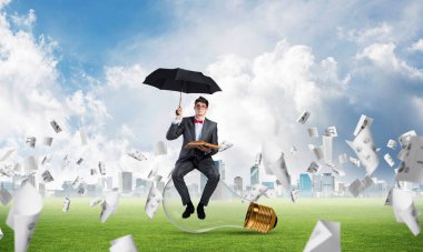 Şemsiyesi ve kitabı olan genç bir iş adamı.