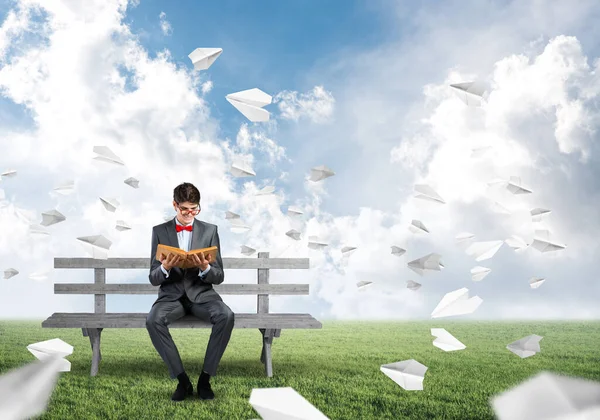 Young student with a book on a bench — Stock Photo, Image