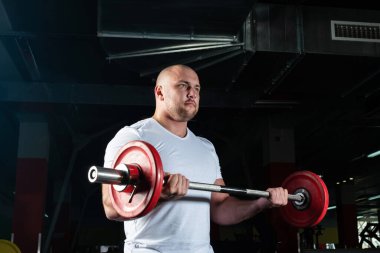 Erkek sporcu halteri kaldırır.