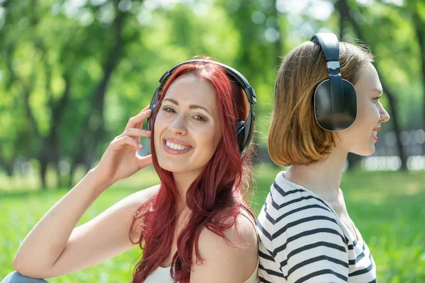 Dos chicas jóvenes en el parque escuchan música. — Foto de Stock