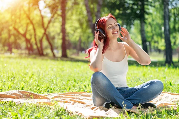 Jovem mulher tem música em um parque de verão — Fotografia de Stock