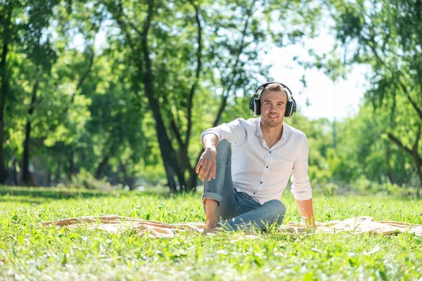 De man in het park luistert naar muziek. — Stockfoto