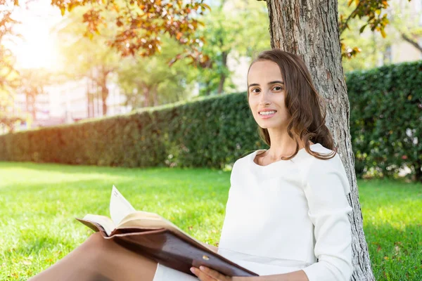 Mooie jonge vrouw met notitieblok in park — Stockfoto