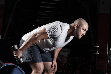 Spor salonunda dambıllarla çarpışan erkek vücut geliştirici.