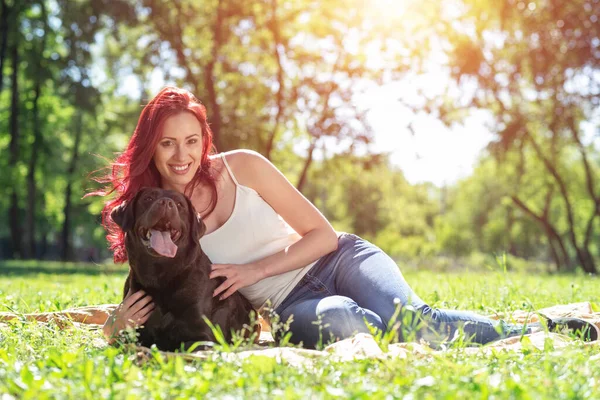 Junge attraktive Frau umarmt ihren Hund im Park. — Stockfoto