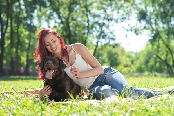 Jovem mulher atraente abraça seu cão no parque. — Fotografia de Stock