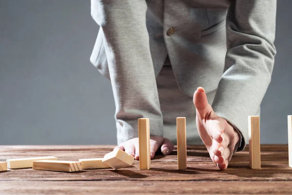 Businesswoman protecting dominoes from falling — Stock Photo, Image