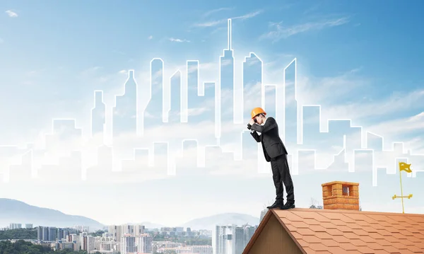 Ingenjör man står på taket och tittar i kikare. Blandade medier — Stockfoto