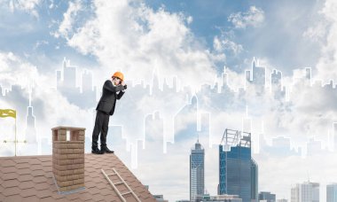 Çatıda duran ve dürbüne bakan mühendis. Karışık ortam