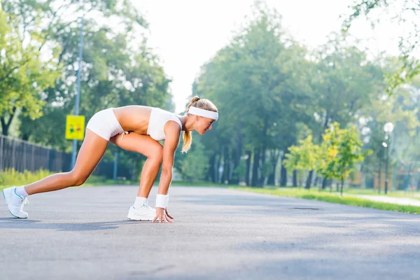 Kvinna löpare står i början pose — Stockfoto