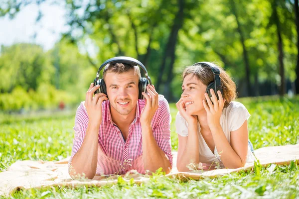 Couple in summer park listening music — Stock Photo, Image