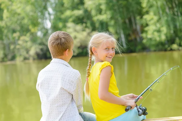 Boy and girl on wooden pier with rod — Stock Photo, Image