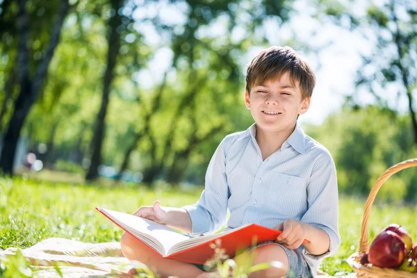 Niño en el parque con libro en las manos — Foto de Stock