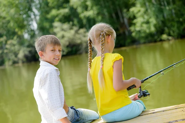 Pojke och flicka på träbrygga med stång — Stockfoto