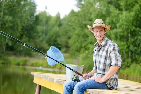Muž sedící na molu s tyčinkou — Stock fotografie