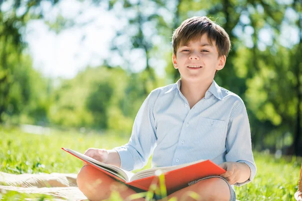 Menino no parque com livro nas mãos — Fotografia de Stock