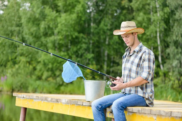 Man sitting on pier with rod — Stock Photo, Image