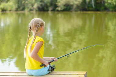 çubuk ile iskele üzerinde oturan kız