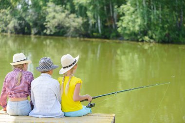 çubuk ile ahşap iskele üzerinde oturan üç çocuk