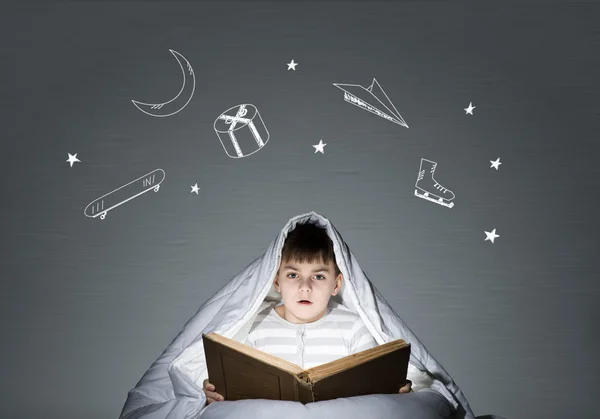 Boy in bed reading book — Stock Photo, Image