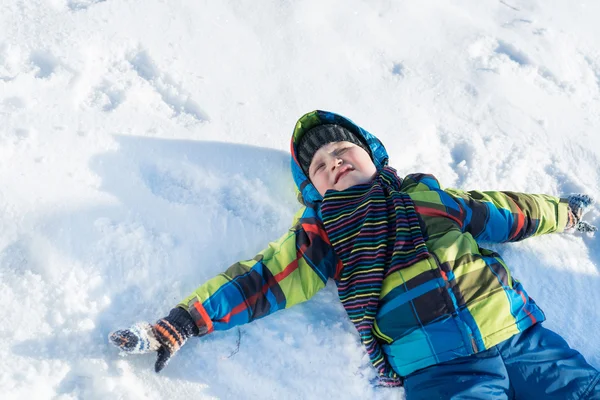 Хлопчик лежить на снігу — стокове фото