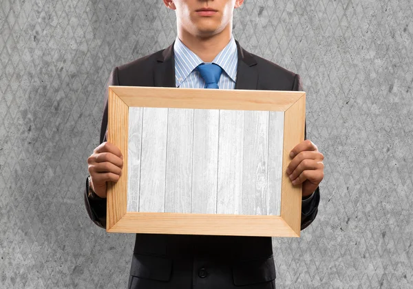 Businessman holding frame with wooden texture — Stock Photo, Image