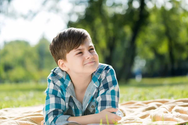 Ragazzo sdraiato su coperta e libro di lettura — Foto Stock