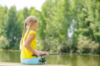 çubuk ile iskele üzerinde oturan kız