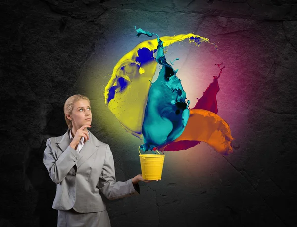 Businesswoman holding bucket with colorful splashes — Stock Photo, Image