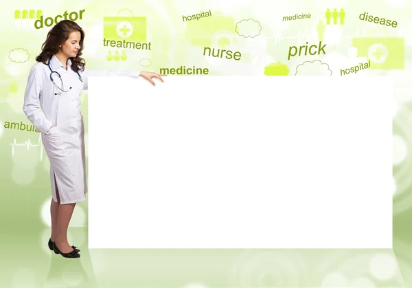 Young woman doctor standing near a blank banner — Stock Photo, Image