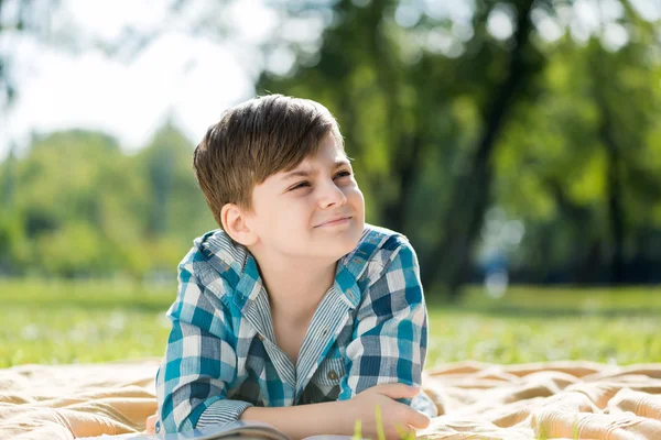 Ragazzo sdraiato su coperta e libro di lettura — Foto Stock