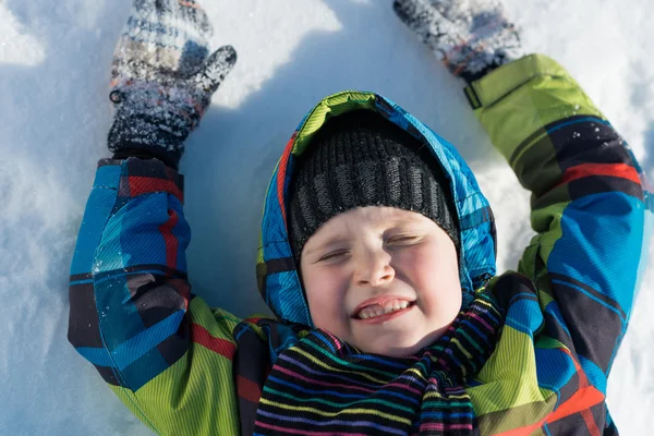 Menino deitado na neve — Fotografia de Stock