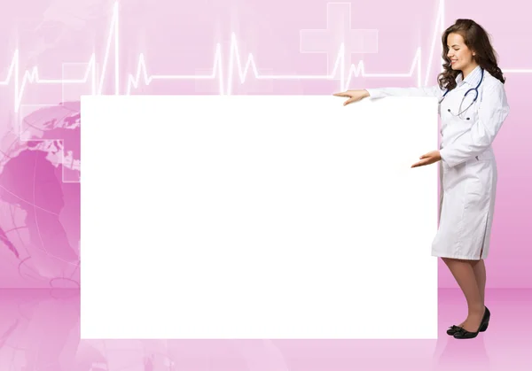 Молодая женщина-врач стоит рядом с пустым плакатом — стоковое фото