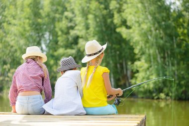 çubuk ile ahşap iskele üzerinde oturan üç çocuk