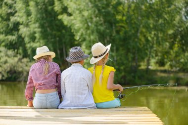 çubuk ile ahşap iskele üzerinde oturan üç çocuk