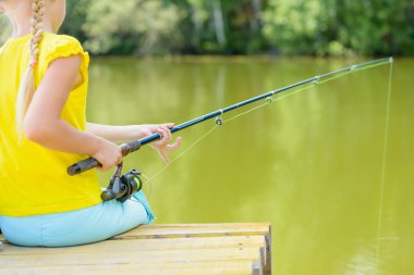 çubuk ile iskele üzerinde oturan kız.