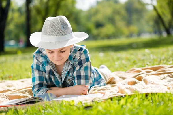 Jongen liggend op deken en lezen van boek — Stockfoto