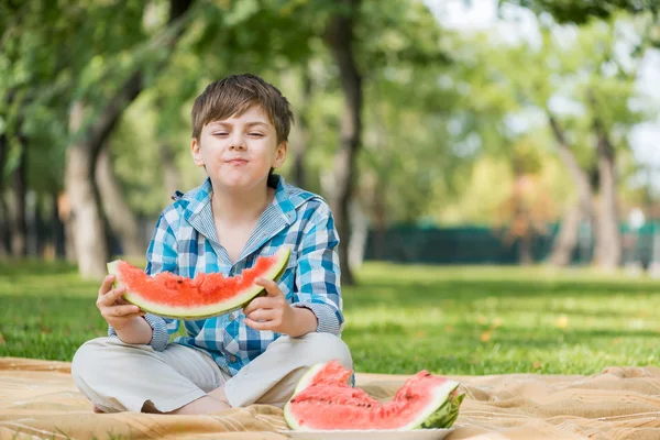 Chlapec jí šťavnatý meloun — Stock fotografie