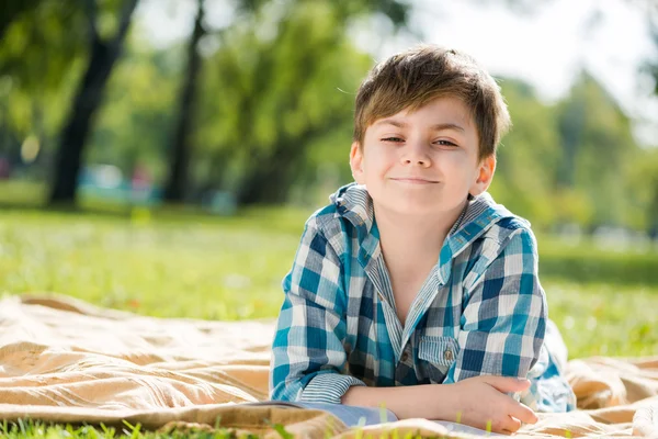 Boy lying on blanket and reading book — Stock Photo, Image