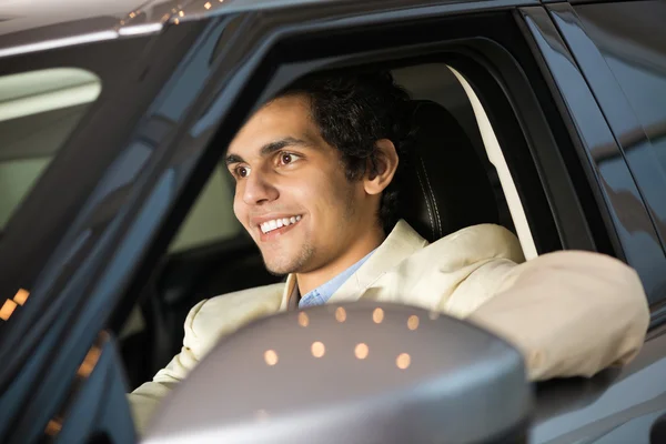 Hombre en la sala de exposición sentado en el coche — Foto de Stock