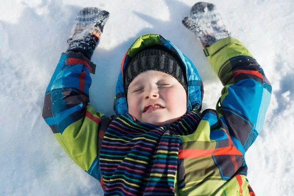 Menino deitado na neve — Fotografia de Stock