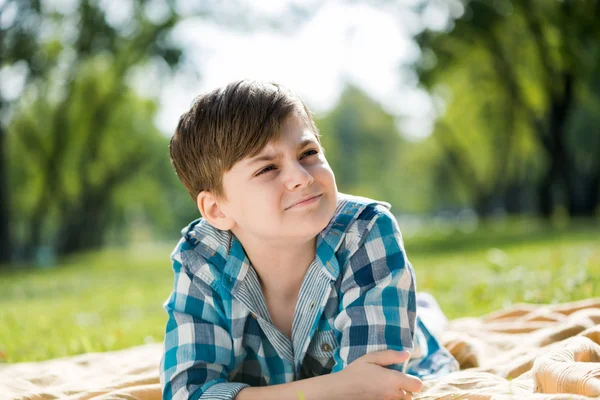 Boy lying on blanket and reading book — Stock Photo, Image