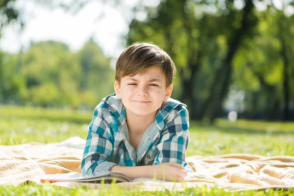 Junge liegt auf Decke und liest Buch — Stockfoto