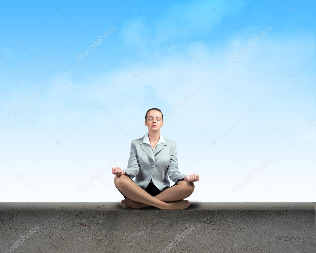 Businesswoman meditating on a parapet