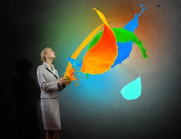 Businesswoman holding bucket with colorful splashes — Stock Photo, Image