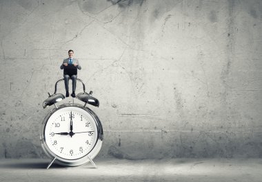 Çalar saat üzerinde oturan işadamı