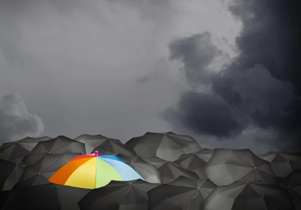 Guarda-chuva colorido entre os pretos — Fotografia de Stock